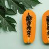 Top view of freshly halved papayas with leafy background, highlighting tropical freshness.
