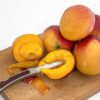 Sliced and whole mangoes on a wooden board with a knife, showcasing vibrant fruit freshness.
