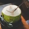 A close-up of a fresh coconut with a straw and spoon, beautifully captured indoors.