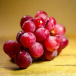 A vibrant bunch of fresh red grapes displayed on a rustic wooden surface.