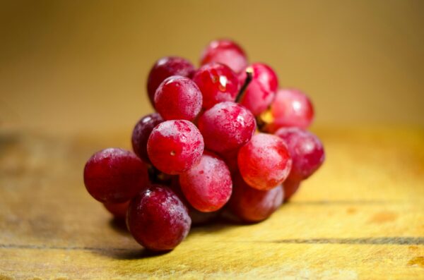 A vibrant bunch of fresh red grapes displayed on a rustic wooden surface.